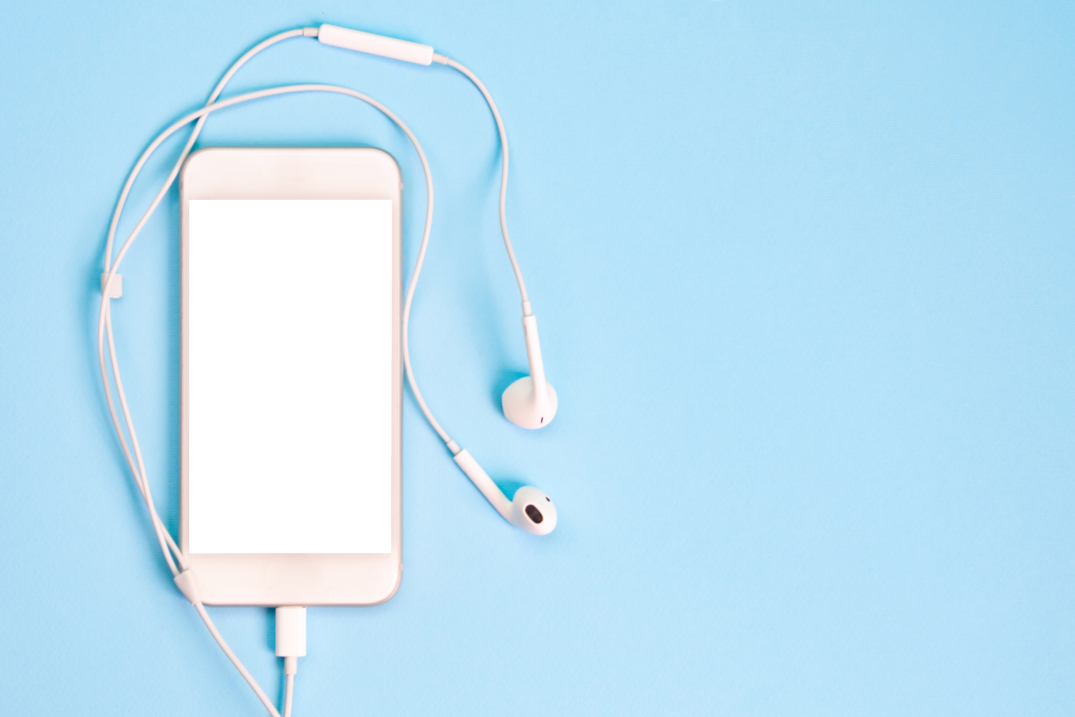 White smartphone on the blue background with headphones. View from above.