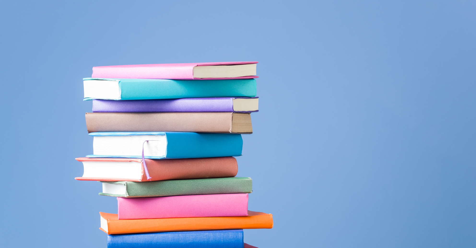Stack Of Multi Colored Books On Blue Background