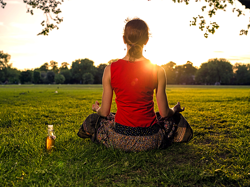 Woman meditating in park at sunset