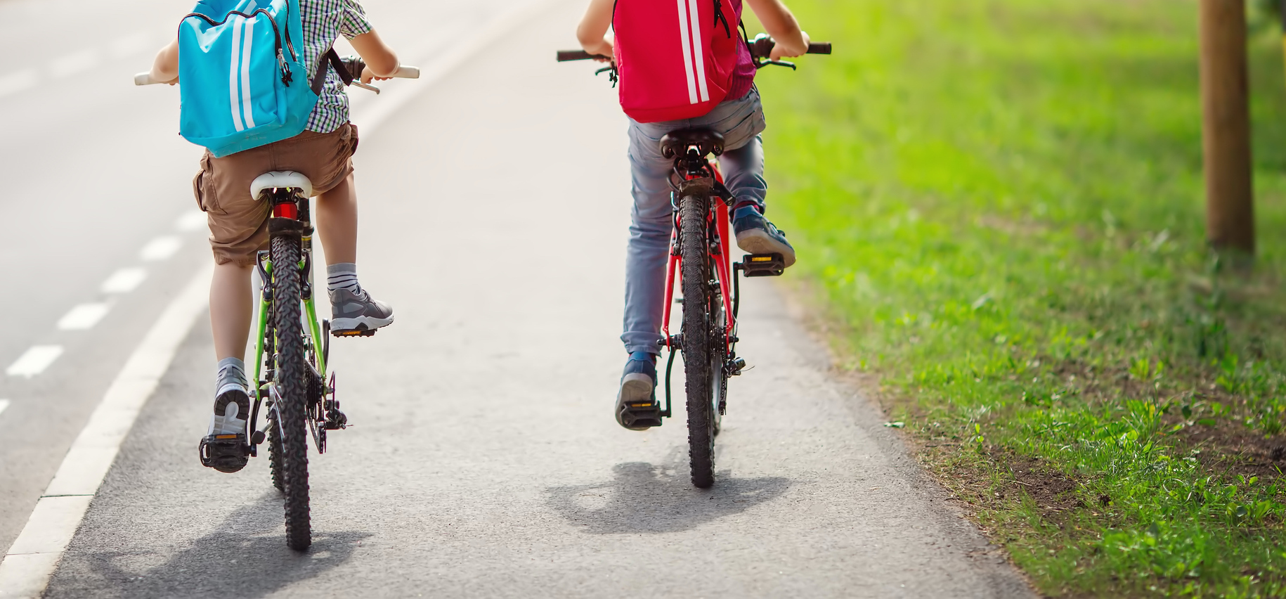 Two boys with backpacks on bicycles going to school.