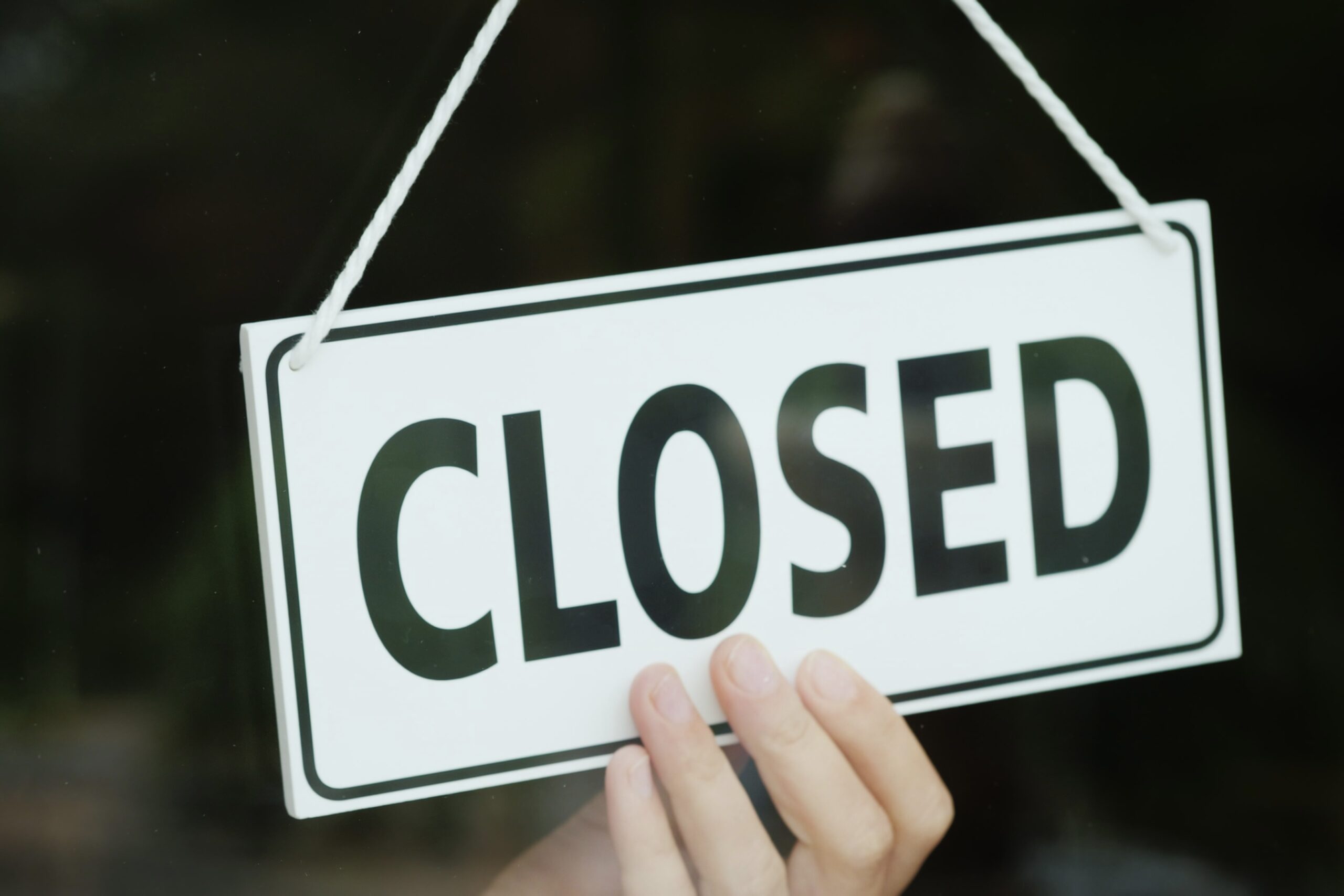 The hand turns the sign with the inscription open to the Closed position. The end of the working day